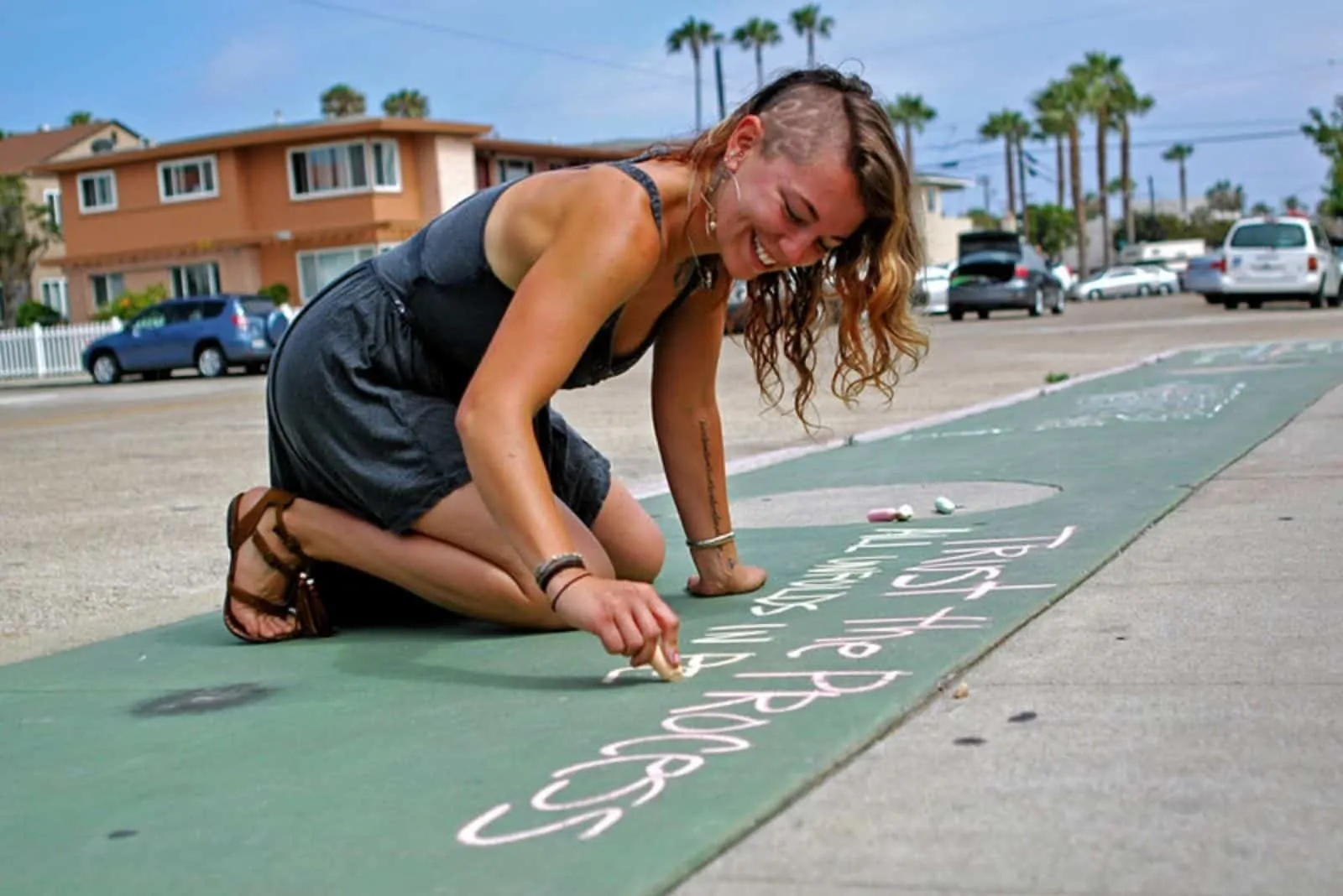 Eine lächelnde Frau schreibt etwas mit Kreide auf die Straße