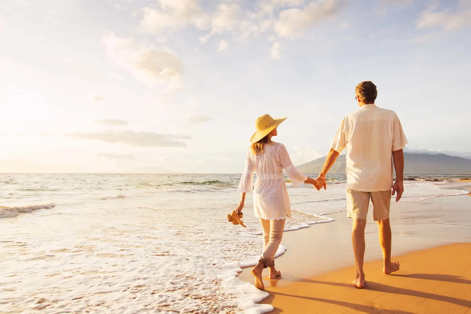 Glückliches romantisches Paar mittleren Alters, das schönen Sonnenuntergangspaziergang am Strand genießt