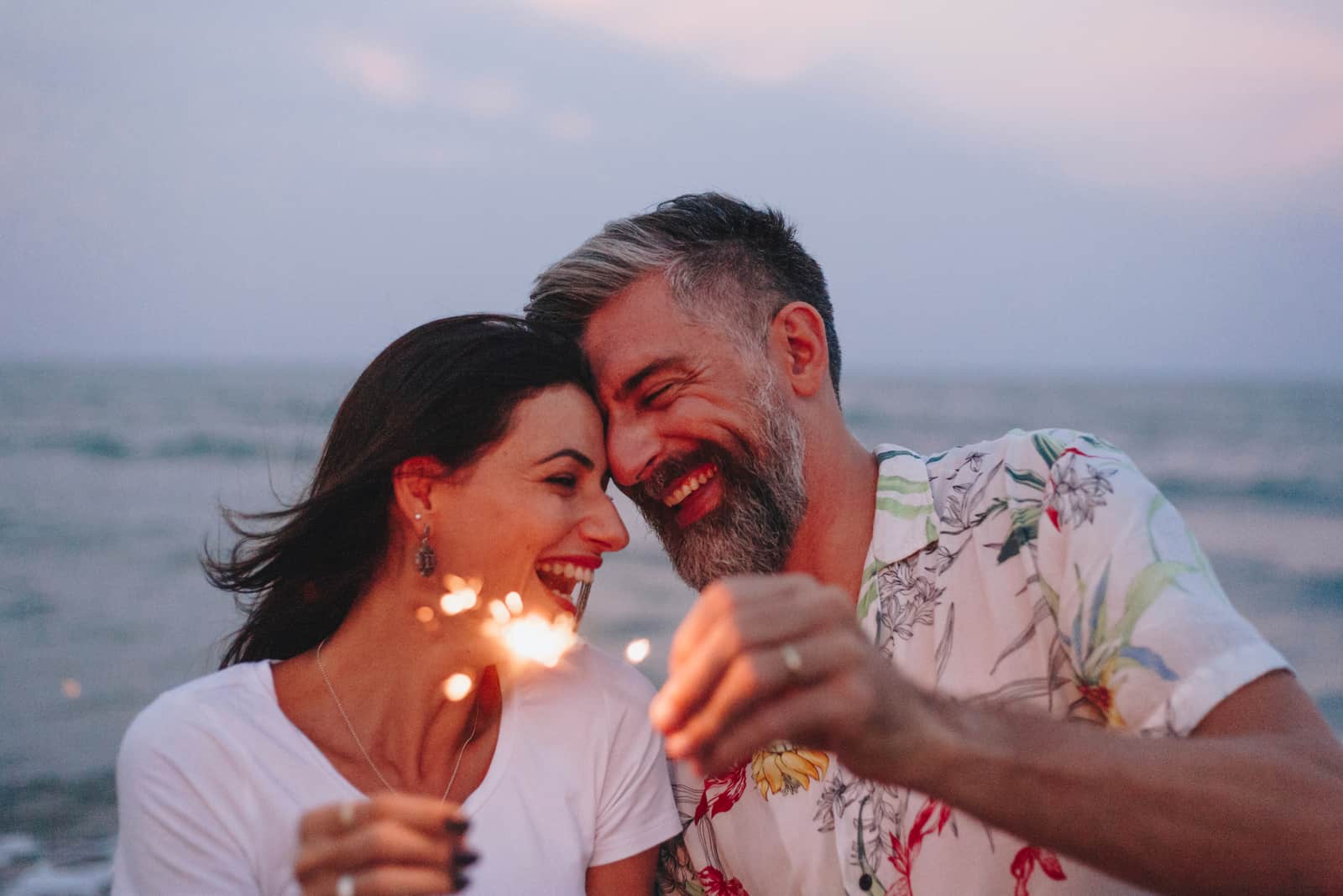 Paar, das mit Wunderkerzen am Strand feiert