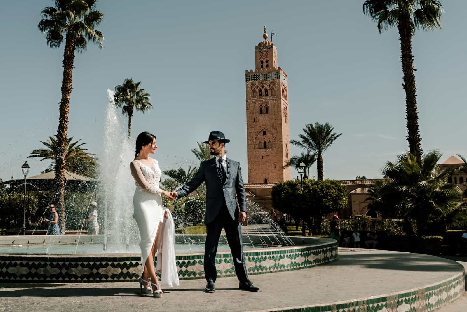 ein Paar als Bräute verkleidet posiert vor der Koutoubia-Moschee in Marokko