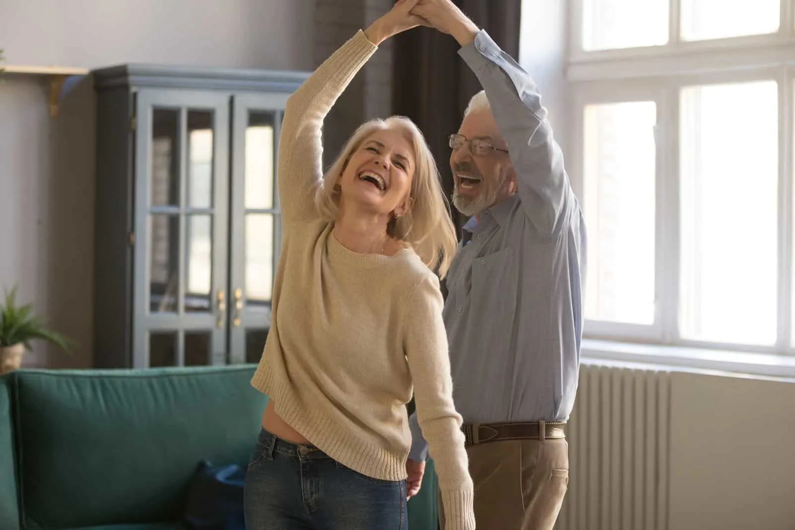 ein lächelndes älteres Ehepaar tanzt im Haus