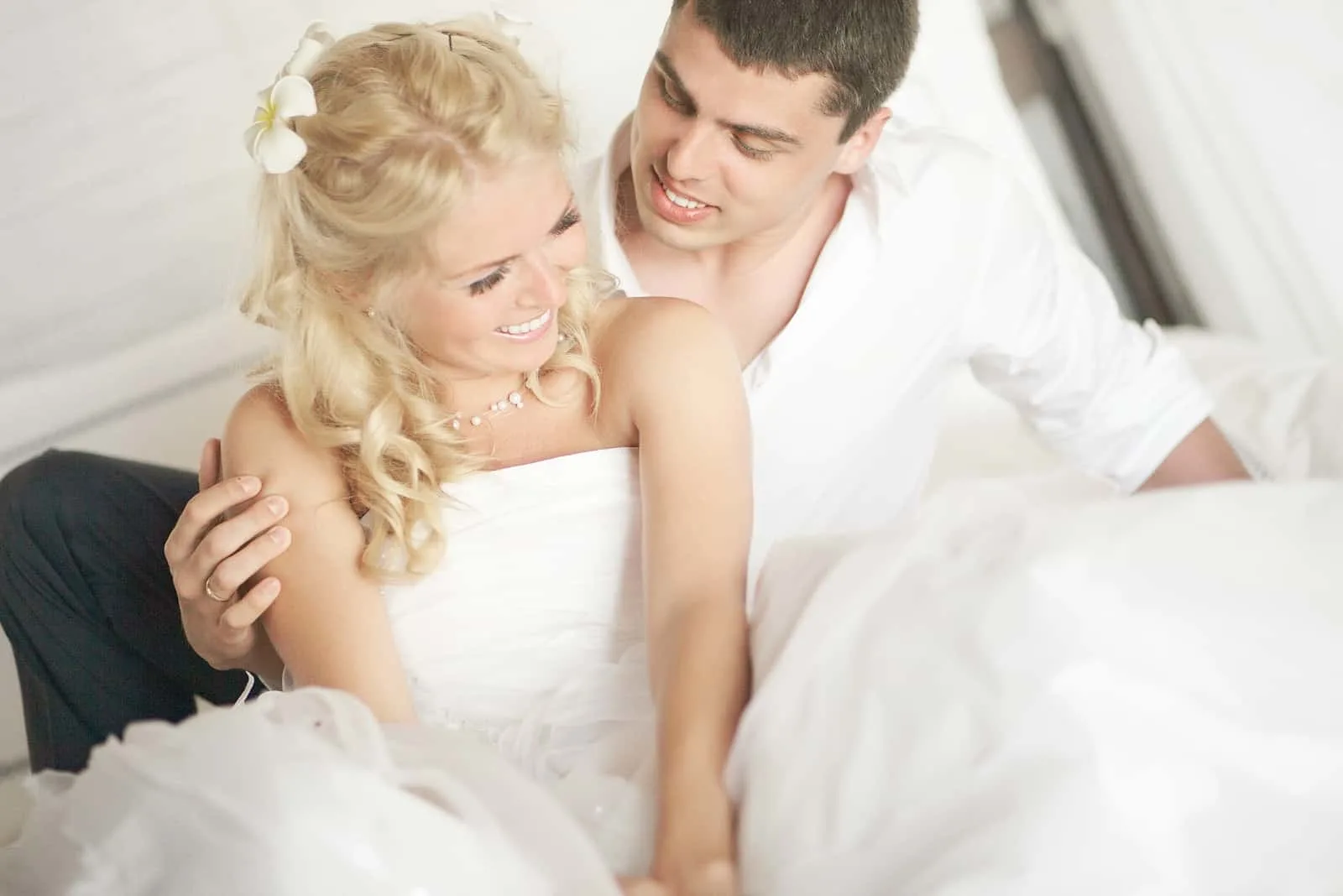 lächelnde Jungvermählten umarmen sich im Bett