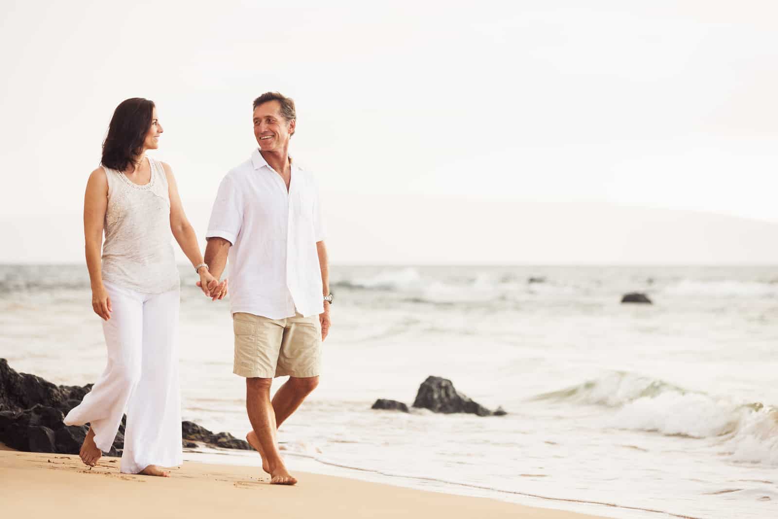Älteres Ehepaar im Ruhestand, das den Sonnenuntergangsspaziergang am Strand genießt