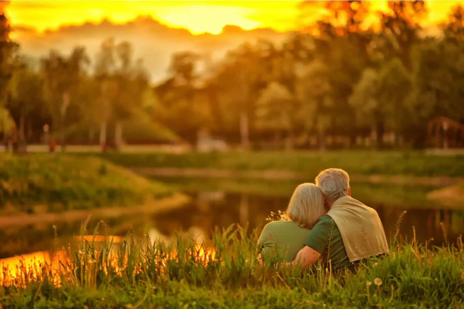 Bei Sonnenuntergang am Ufer des Sees umarmt sich ein älteres Ehepaar