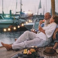 Ein älteres Liebespaar isst Obst und trinkt Champagner auf einer Yacht