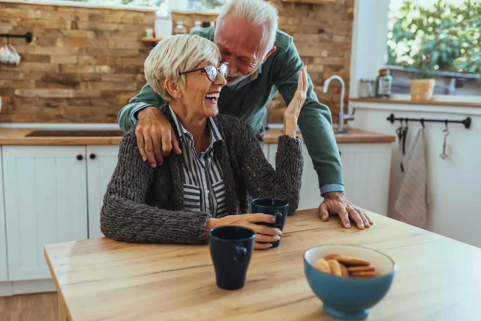 Ein lächelndes älteres Ehepaar umarmt sich in der Küche