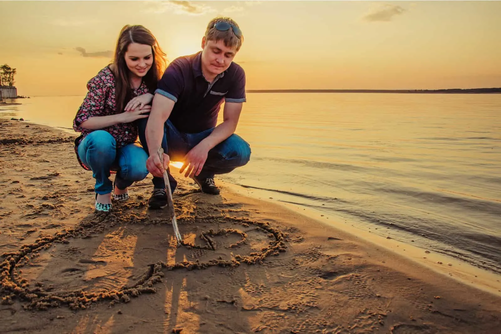 Ein verliebtes Paar zieht ein Herz an einen Sandstrand