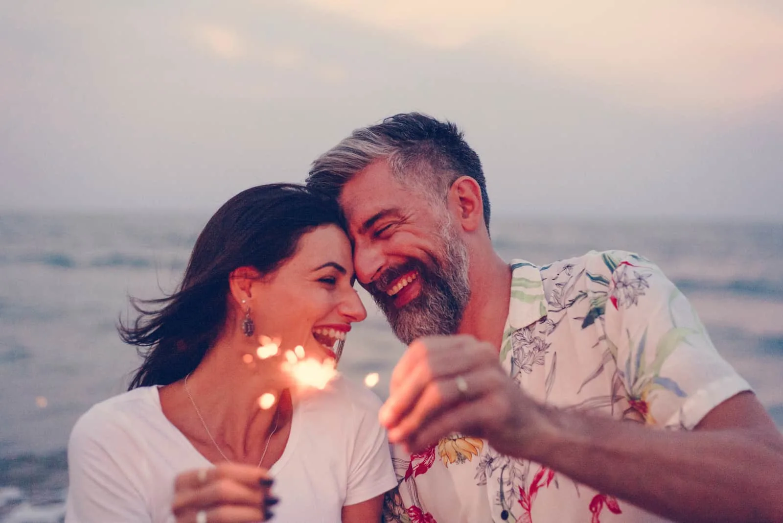 glückliches Paar, das mit Wunderkerzen am Strand feiert