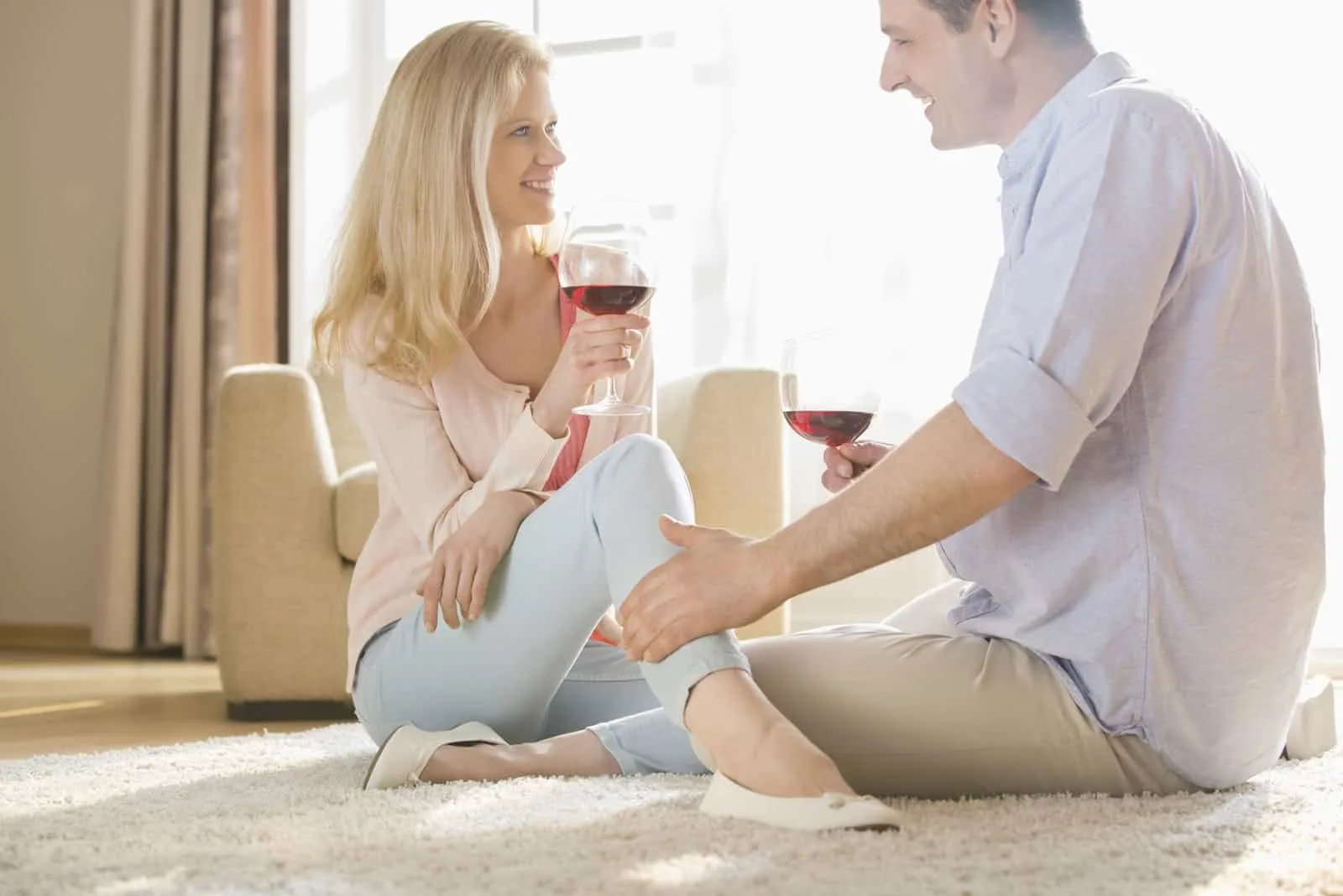 Liebevolles Paar, das sich beim Trinken von Rotwein zu Hause ansieht