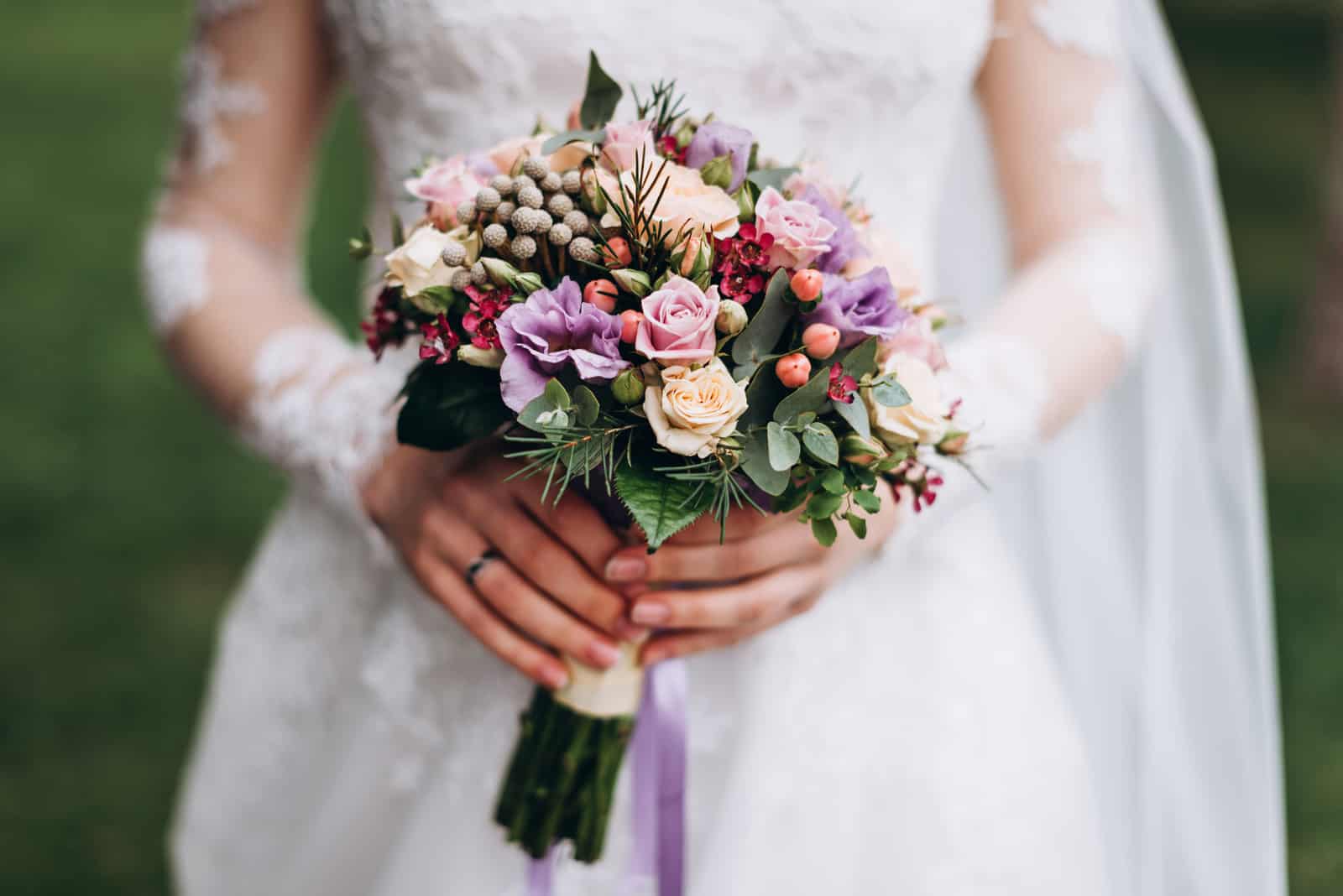Braut in einem weißen Hochzeitskleid hält einen Hochzeitsstrauß