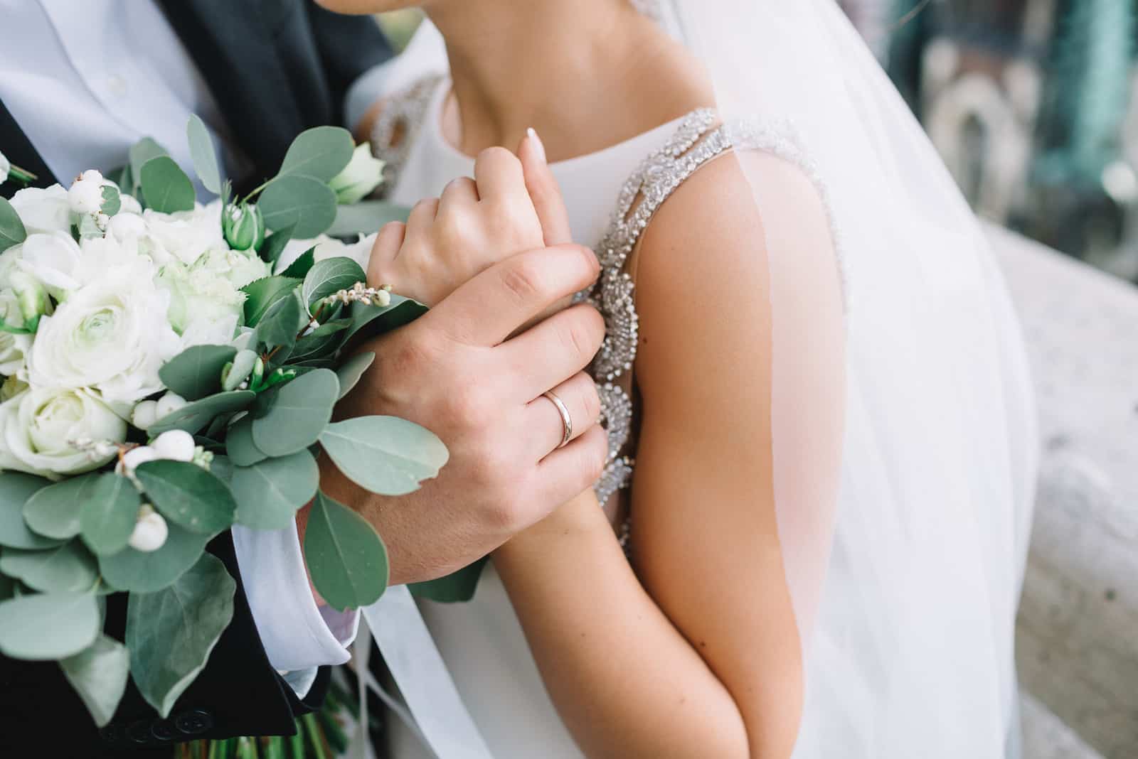 Die Hand des Bräutigams hält das Armband der Braut zärtlich