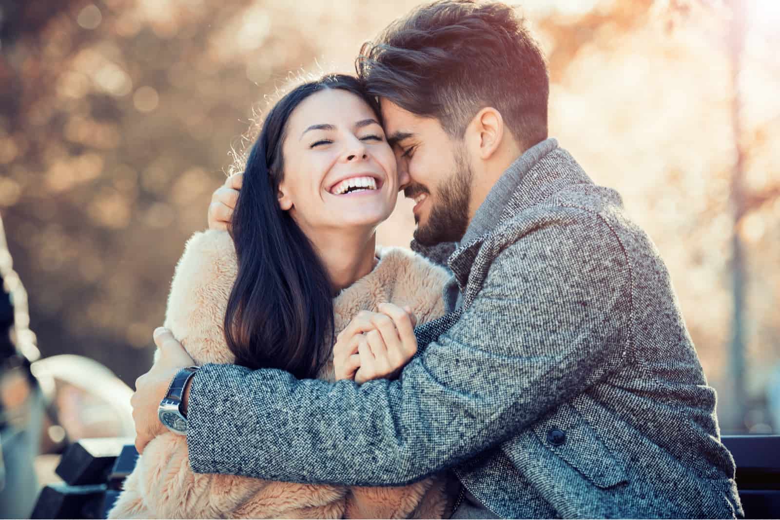 Glückliches junges Paar, das draußen umarmt und lacht