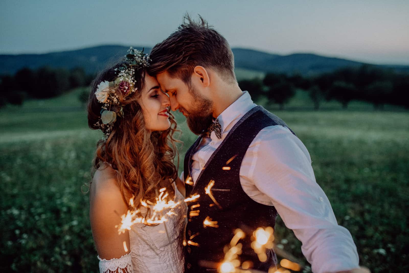 Schönes Brautpaar mit Wunderkerzen auf einer Wiese