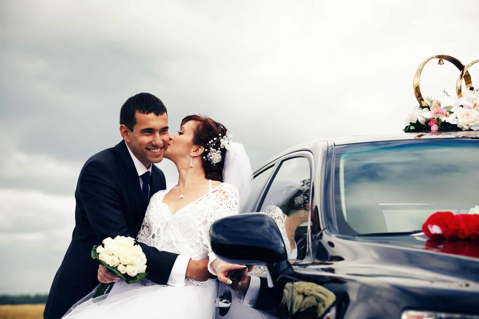 Schönes glückliches Brautpaar in der Nähe von Hochzeitsauto wedding