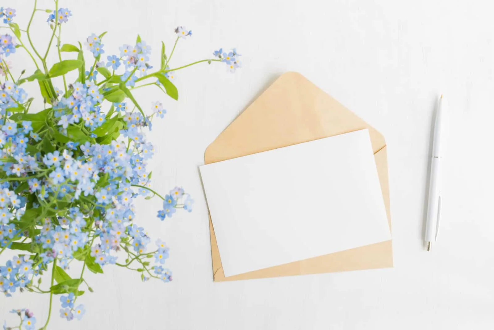 weiße Grußkarte und Umschlag mit blauen Blumen