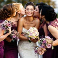 Brautjungfern küssen schöne Braut draußen stehend