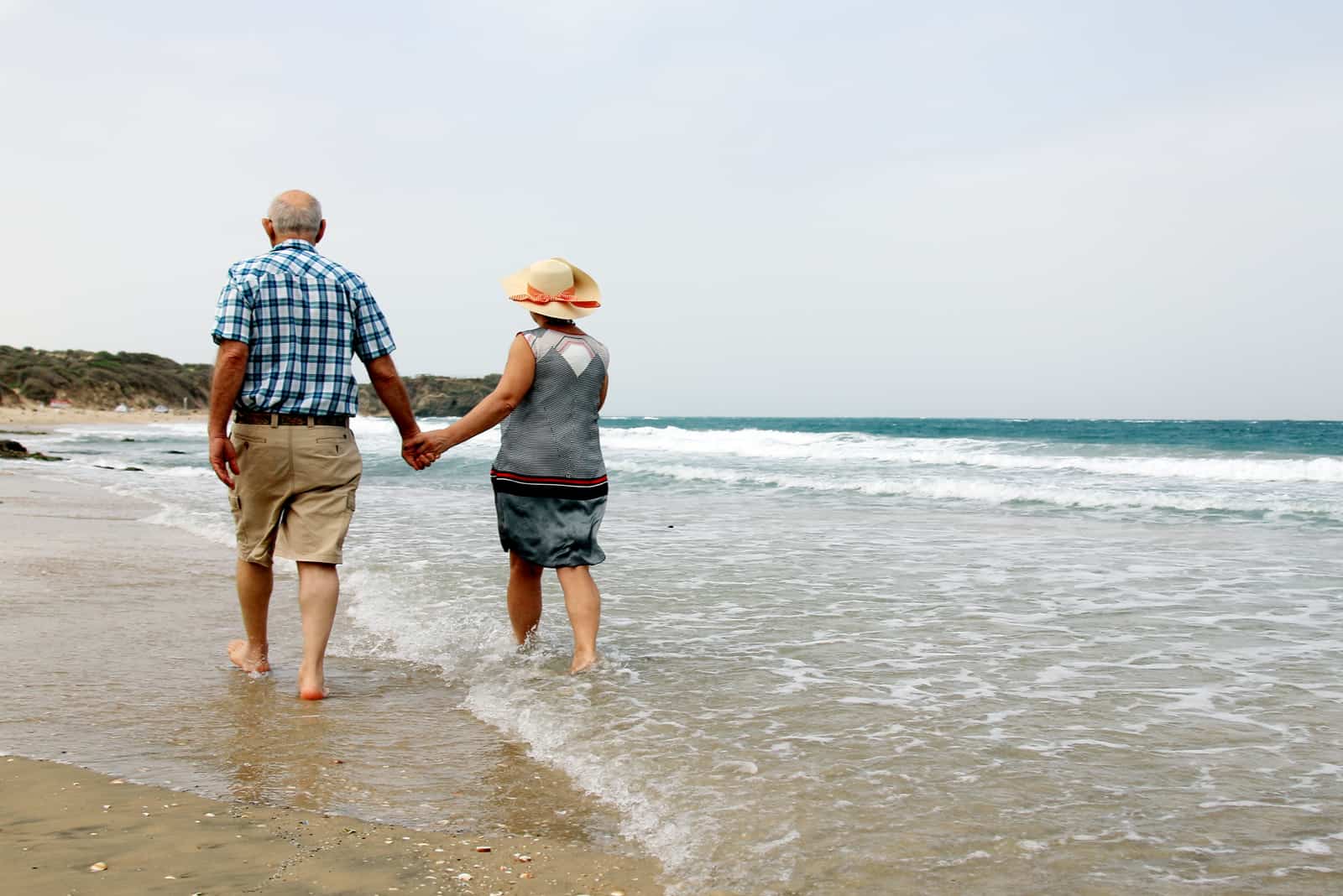 Glückliches älteres Paar, das zusammen an einem Strand spazieren geht