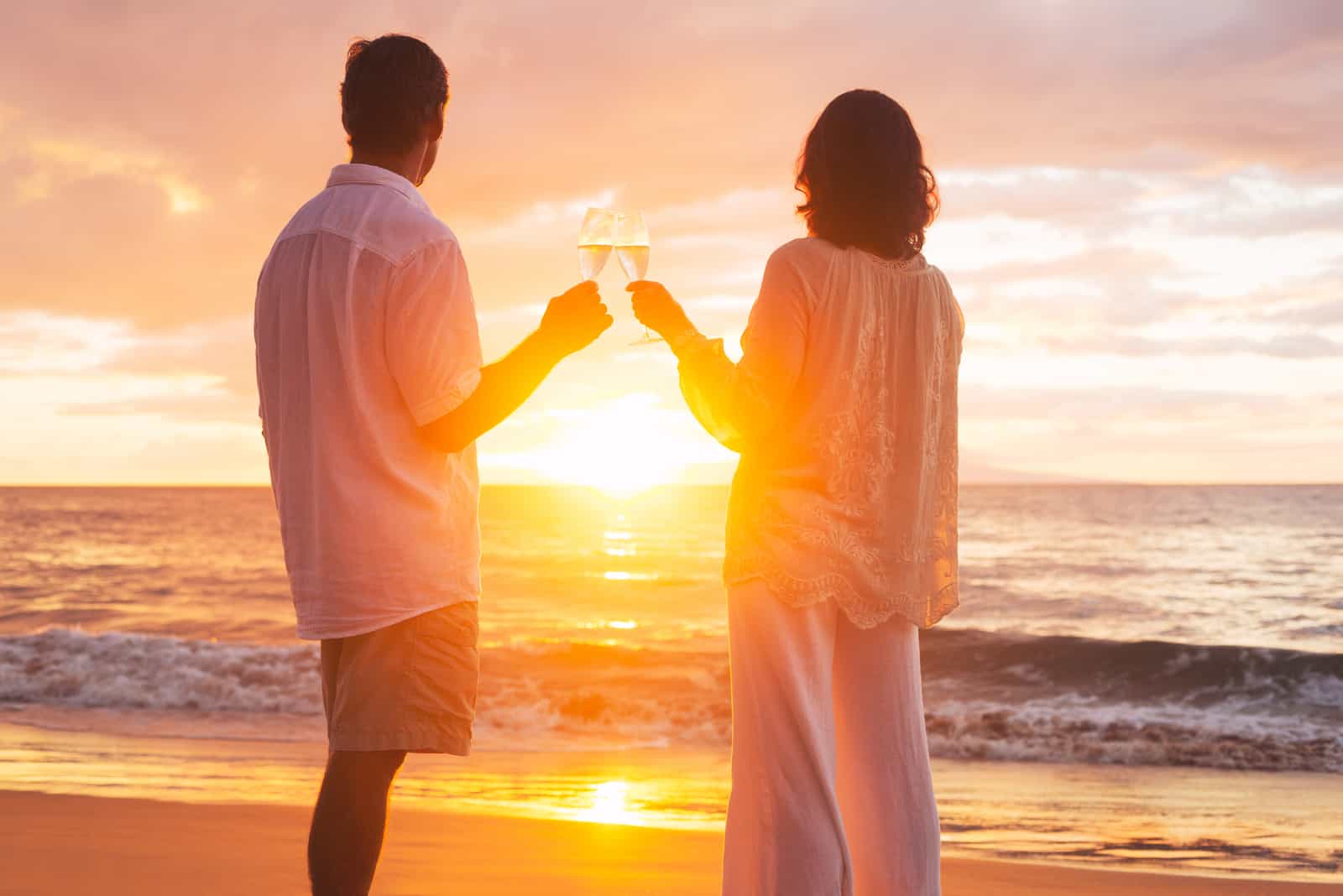 Glückliches romantisches Paar, das ein Glas Champagner bei Sonnenuntergang genießt
