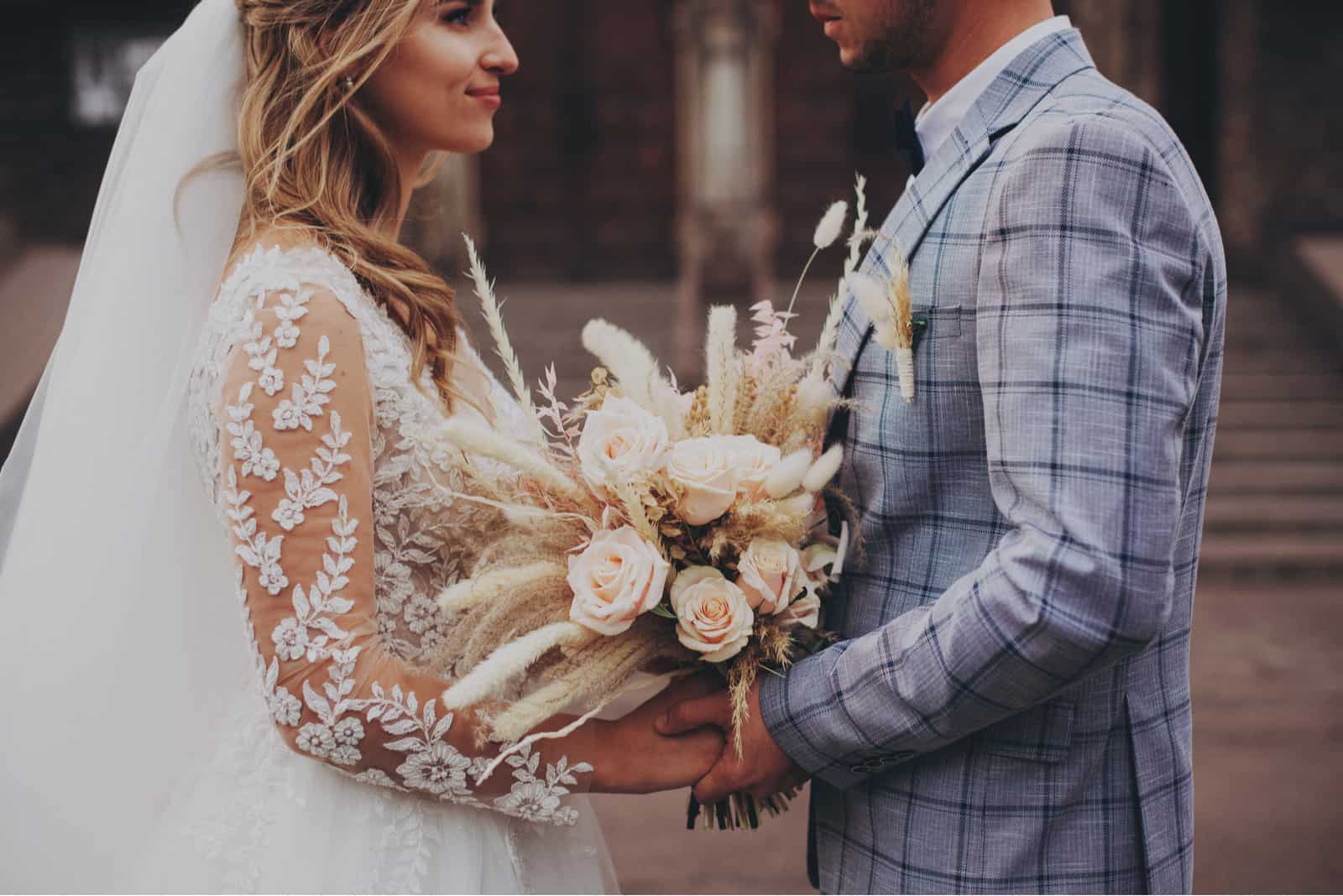 Hübsche Braut und stilvoller Bräutigam mit Boho-Blumenstrauß