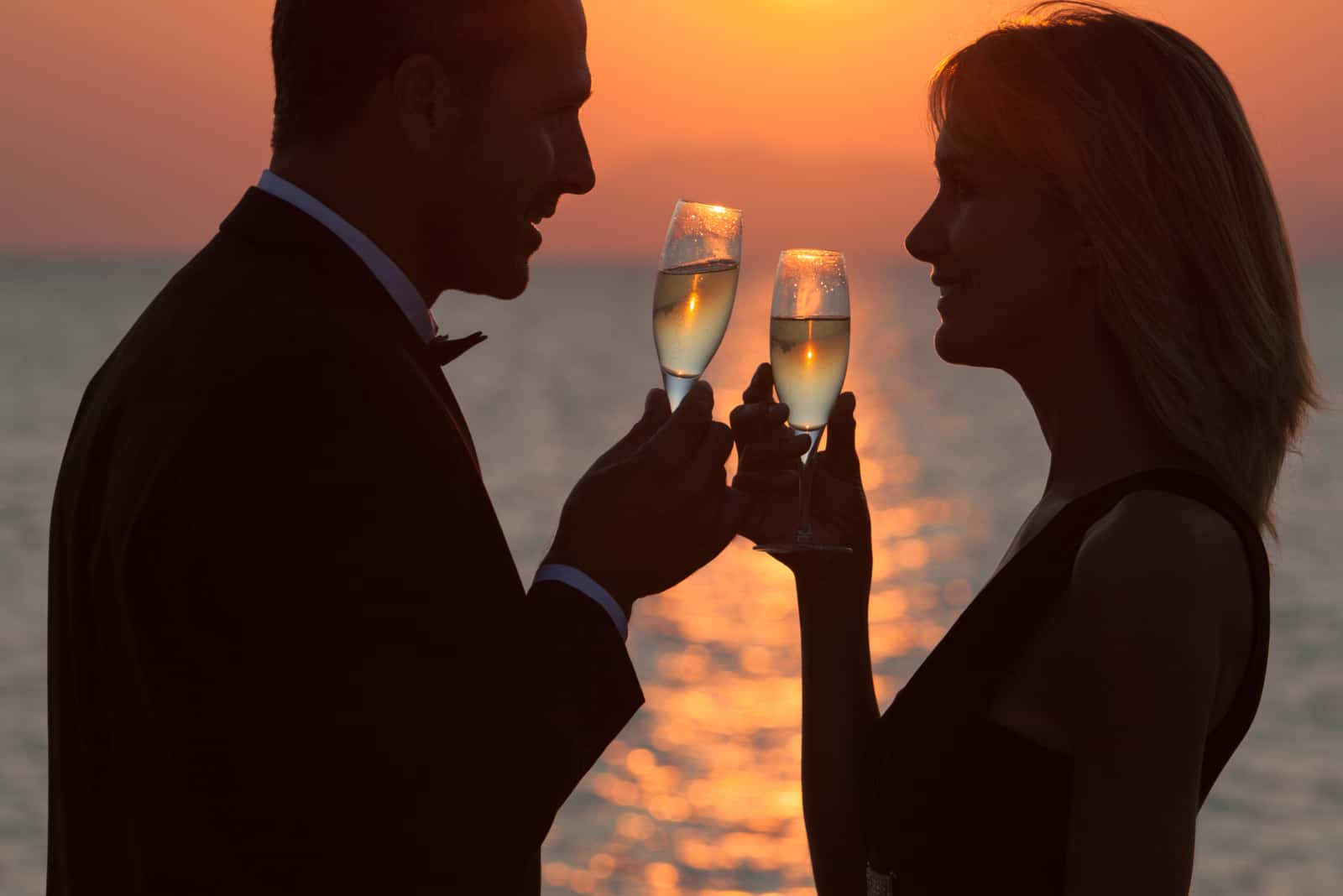 Paar bei Sonnenuntergang am Strand mit Gläsern Champagner