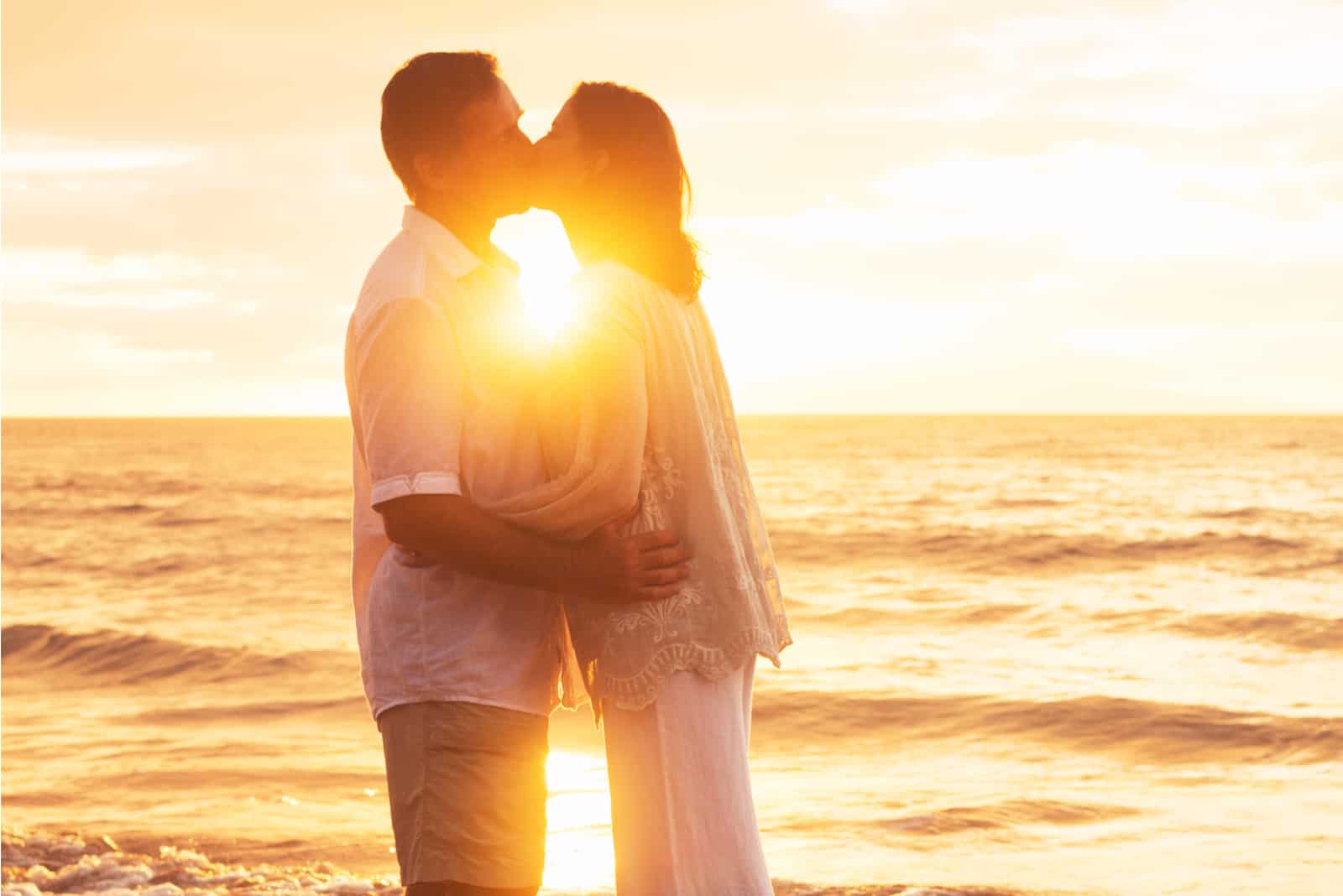 Paar küsst sich bei Sonnenuntergang am Strand