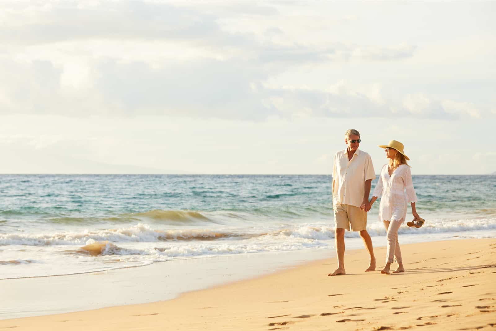 Paar mittleren Alters, das einen wunderschönen Sonnenuntergangsspaziergang am Strand genießt