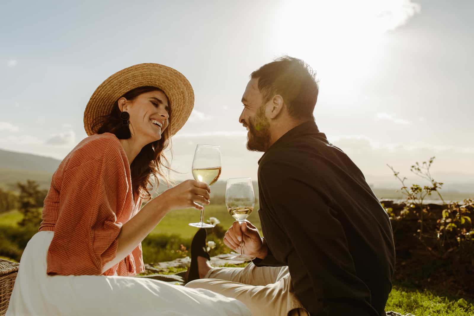 Romantisches Paar sitzt in einem Weinberg und trinkt Wein