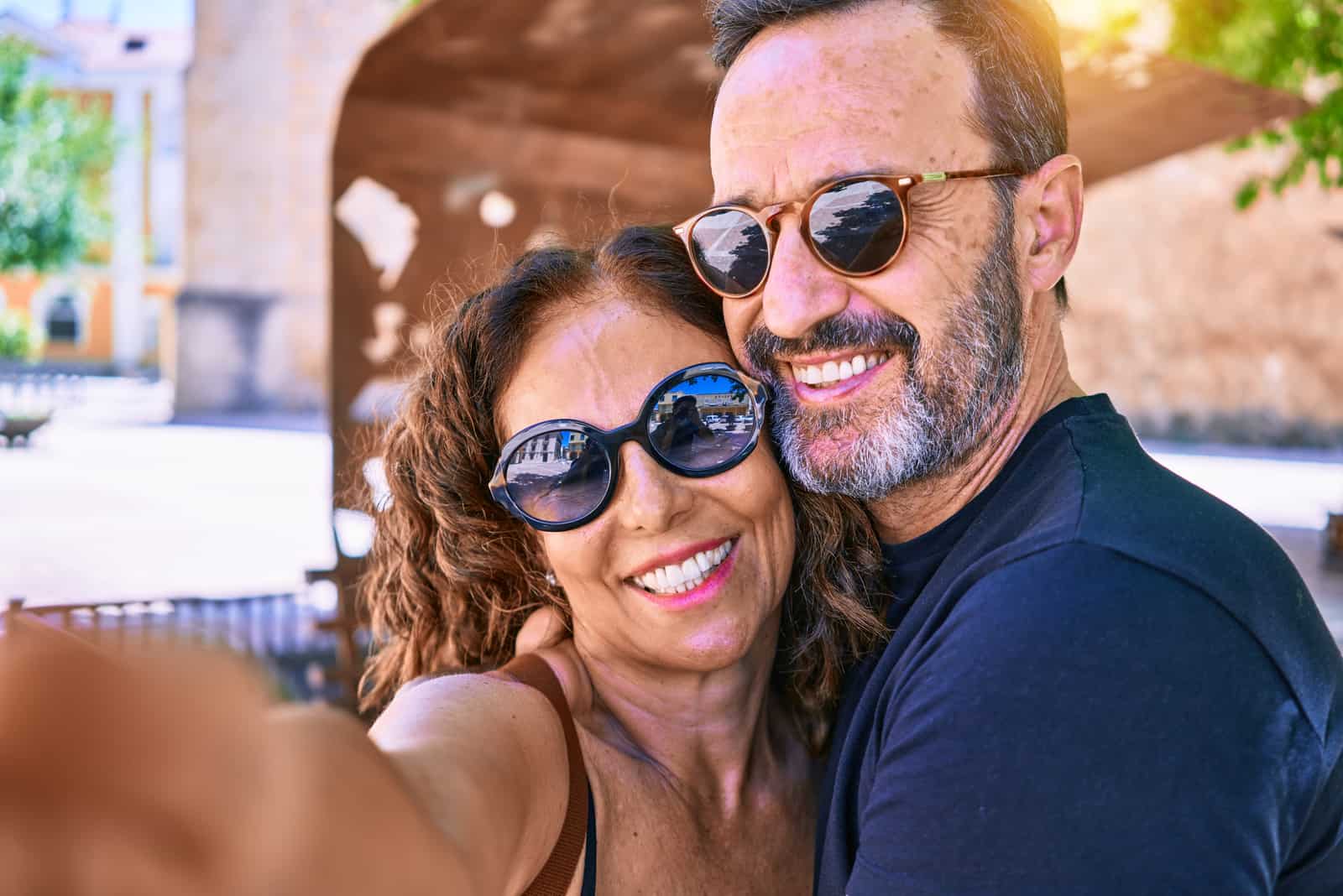 Schönes Paar mittleren Alters in Freizeitkleidung und Sonnenbrille lächelnd