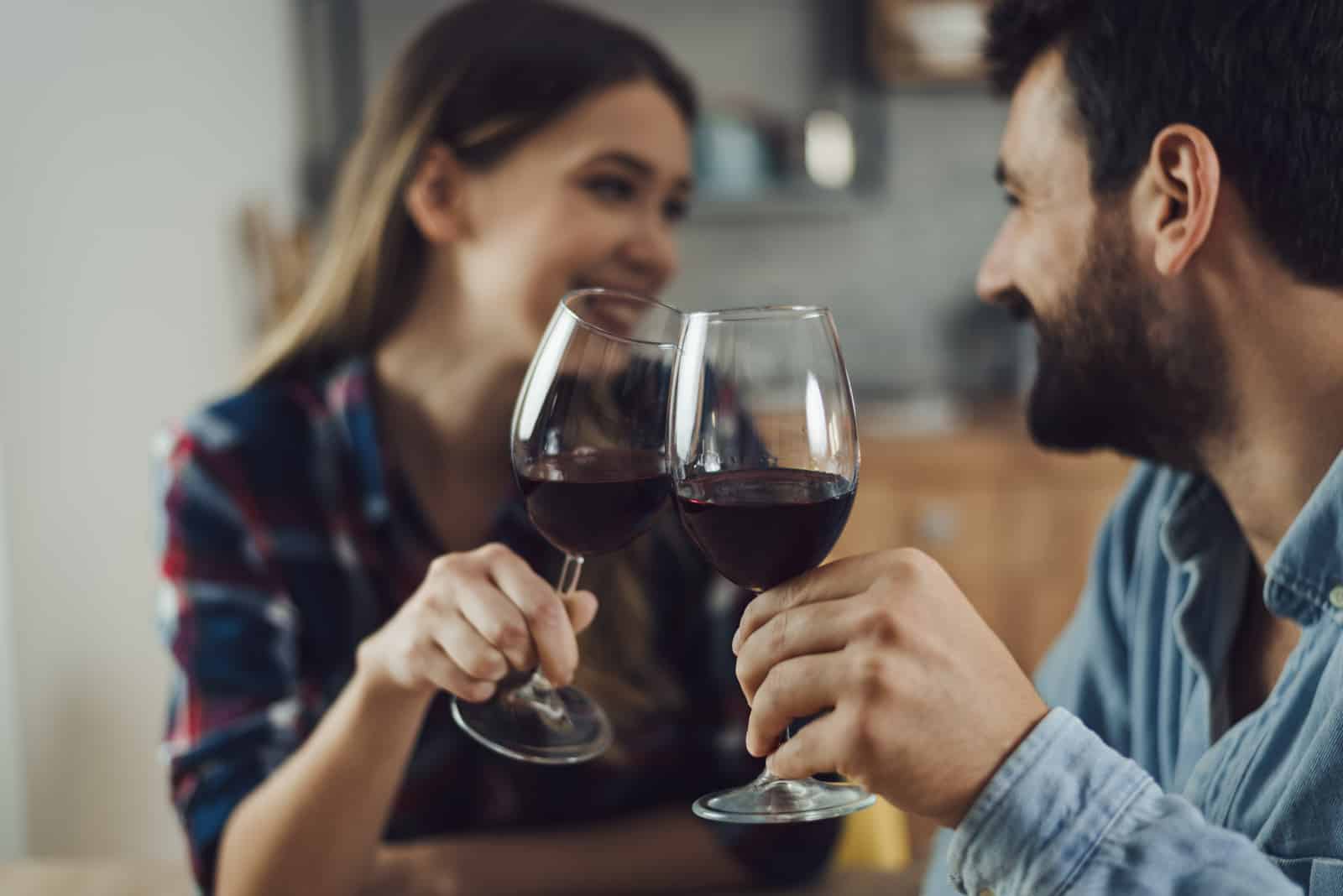 junges Paar, das zu Hause mit Wein anstößt