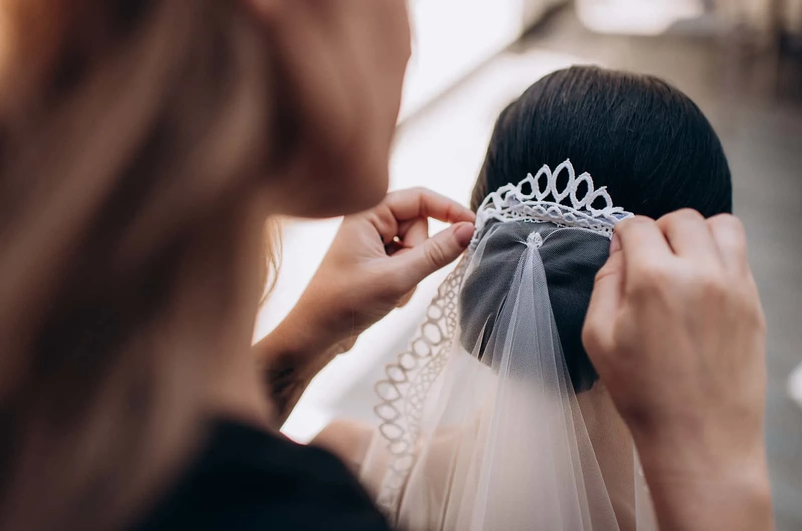 Frau legt der Braut einen Schleier ins Haar