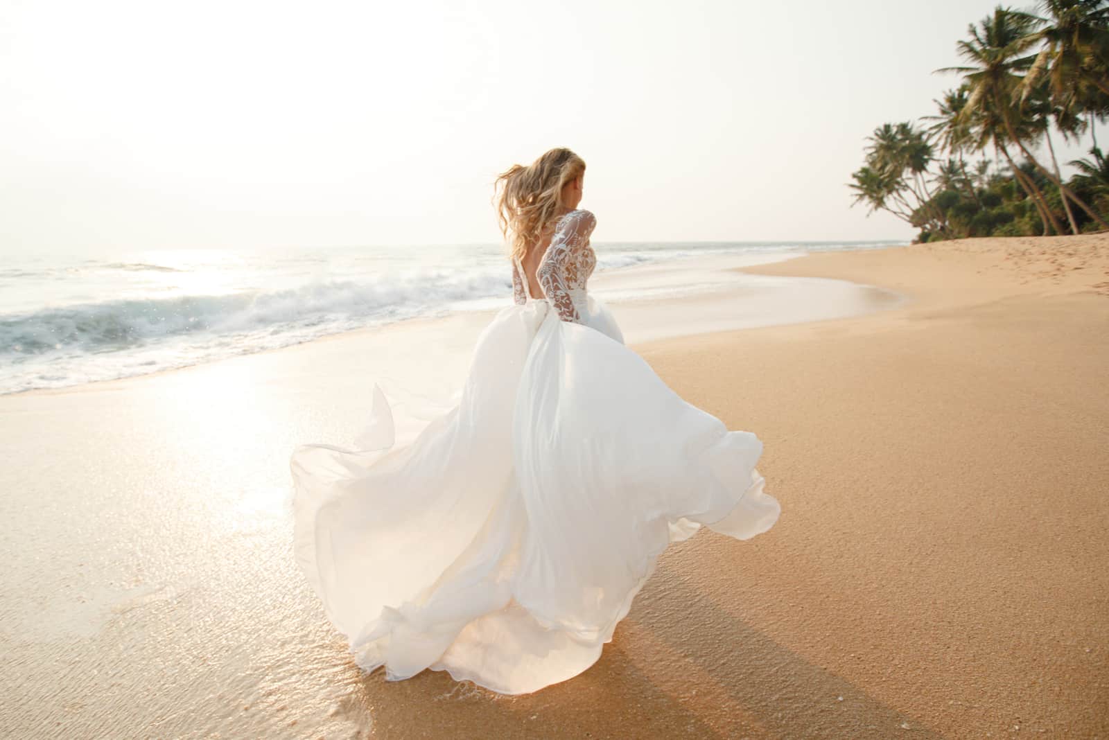 Glückliche junge Brautfrau im weißen Kleid läuft