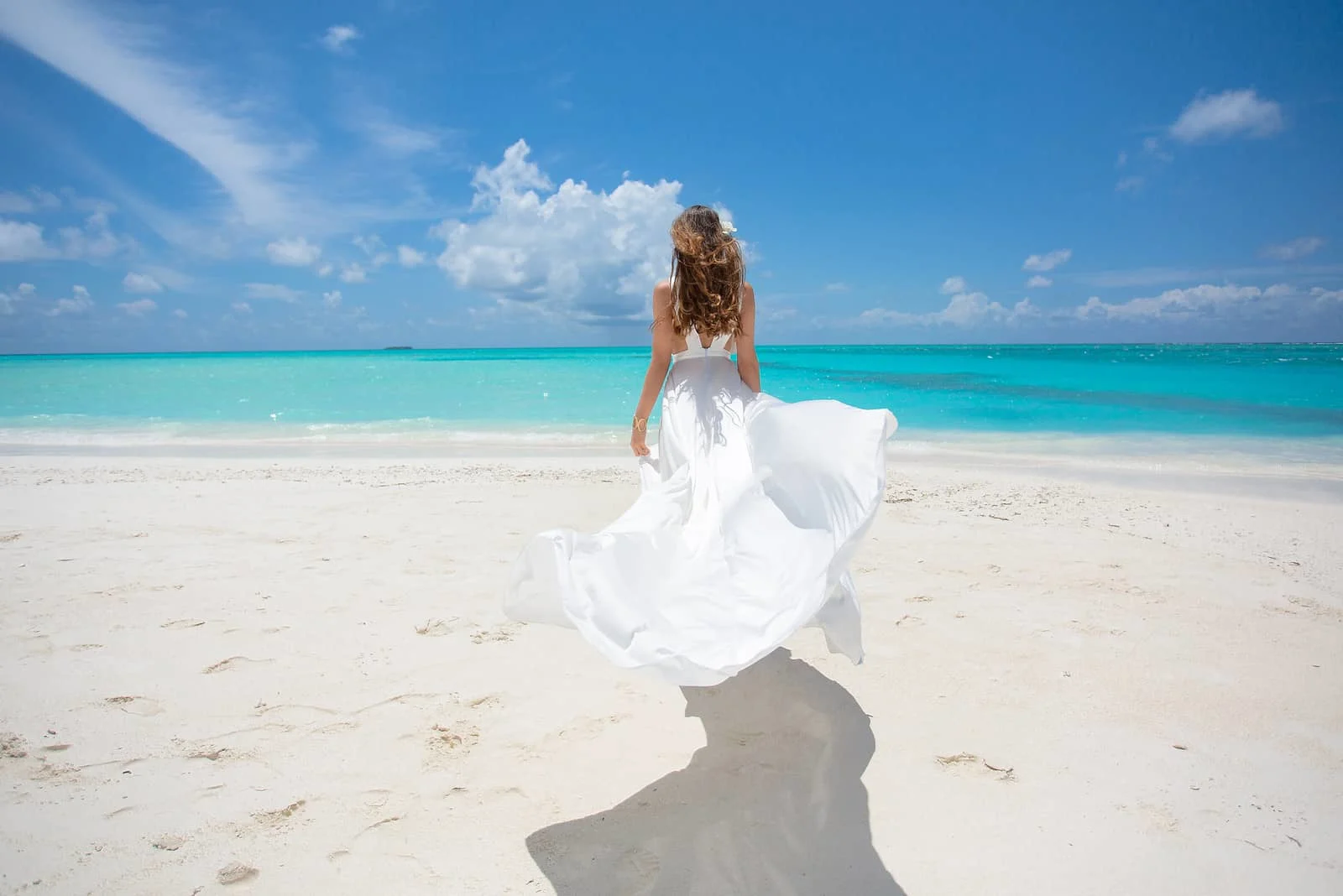 Junge Frau am Strand der tropischen Insel im weißen Kleid
