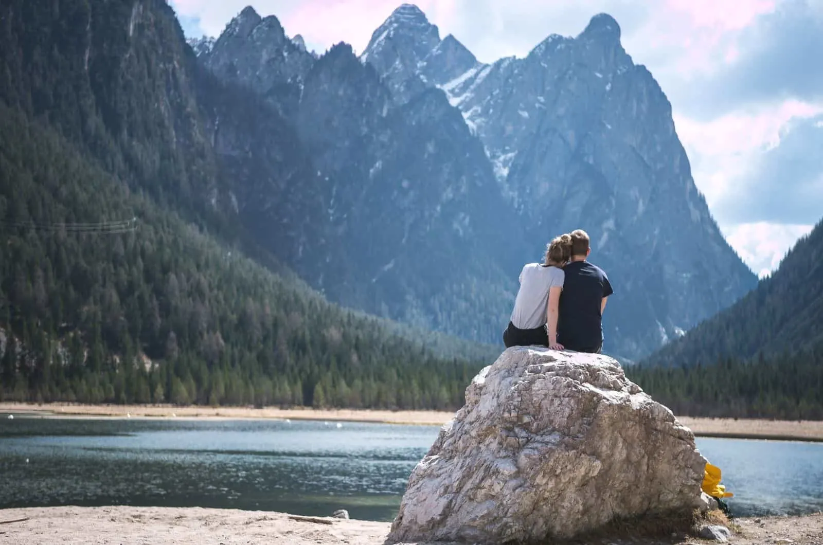 Paar sitzt auf einem Felsen in der Nähe des Sees