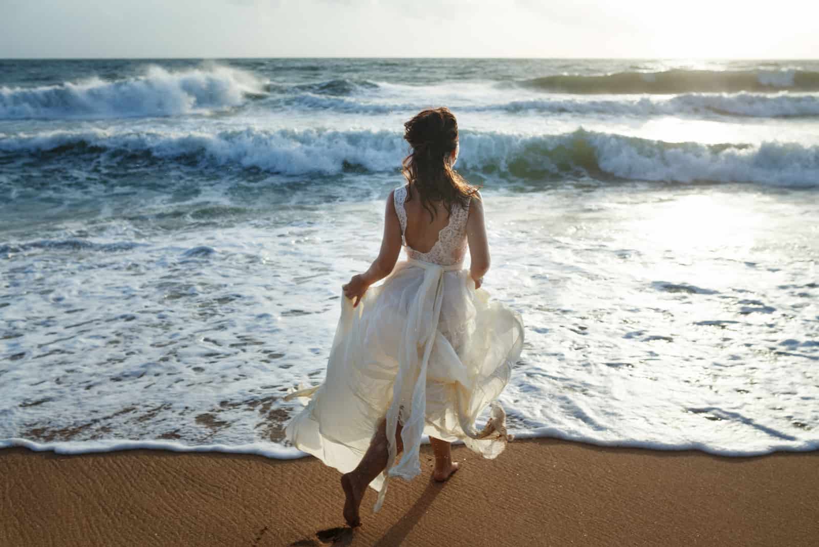 Schöne Braut, die am Strand läuft