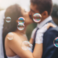 Hochzeitspaar küsst sich mit Blasen herum