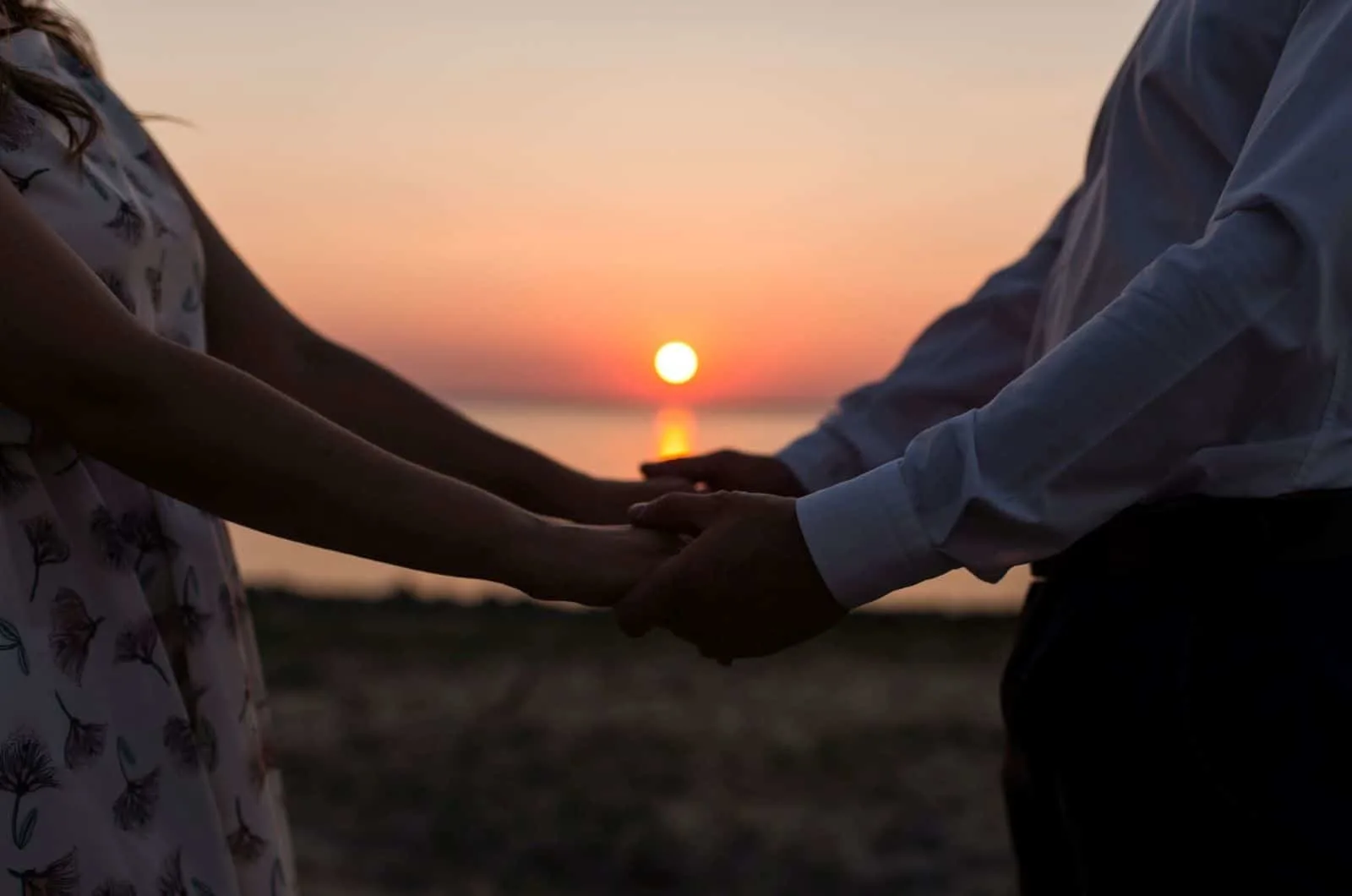 Paar hält Händchen bei Sonnenuntergang