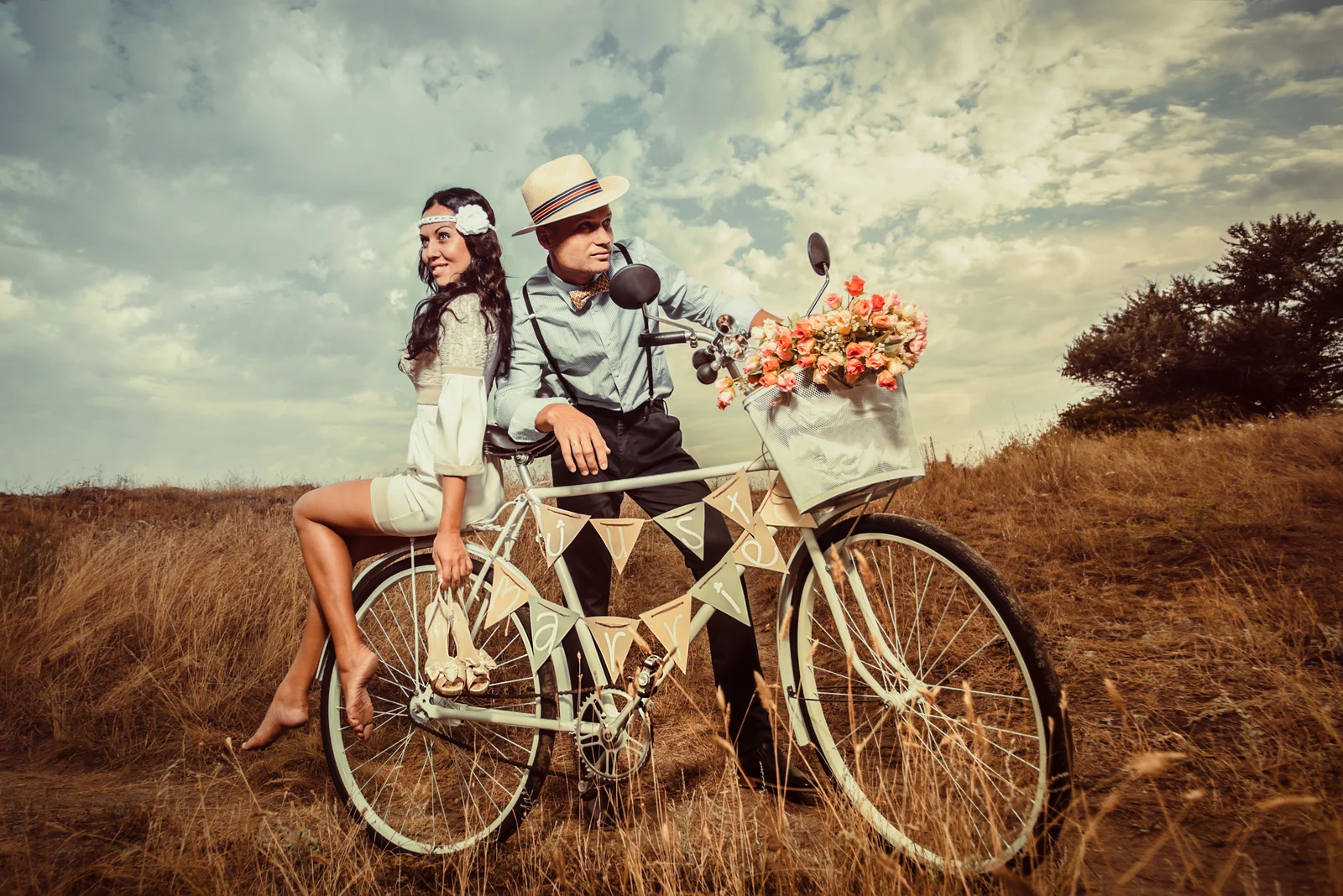 Braut und Bräutigam posieren mit einem Fahrrad