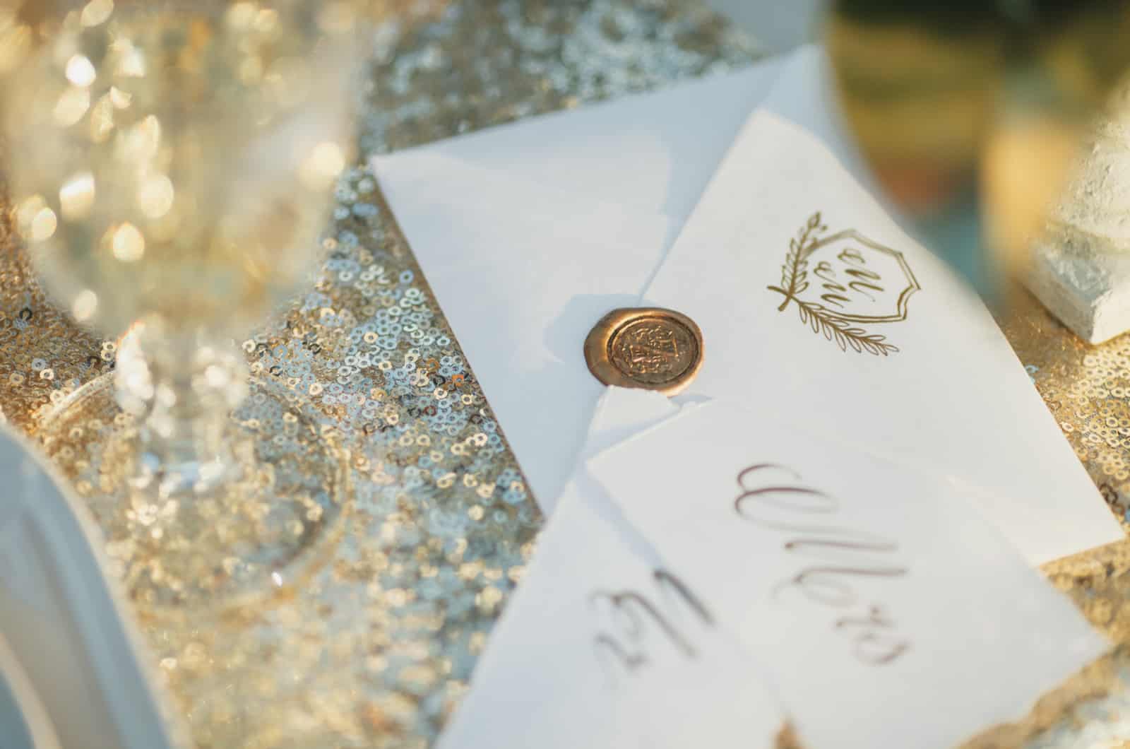 Hochzeitseinladungen mit Goldstempel auf glitzernder Oberfläche