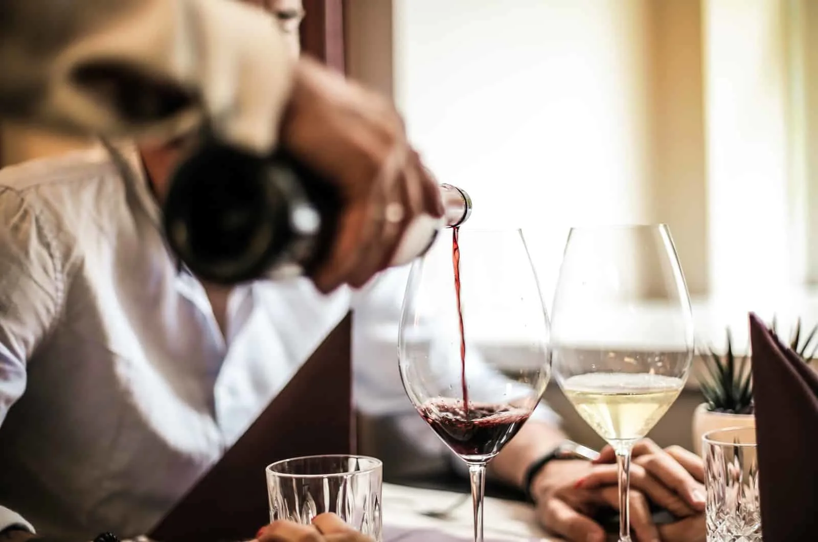 Kellner schenkt Wein in Glas ein