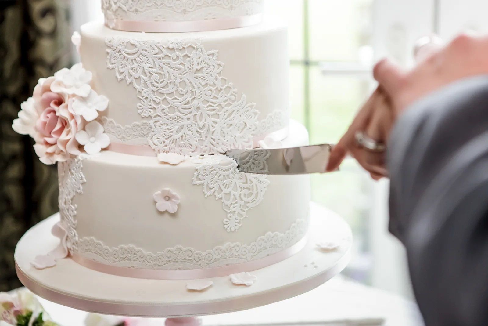Nahaufnahme von Brautpaaren schneiden weißen Kuchen