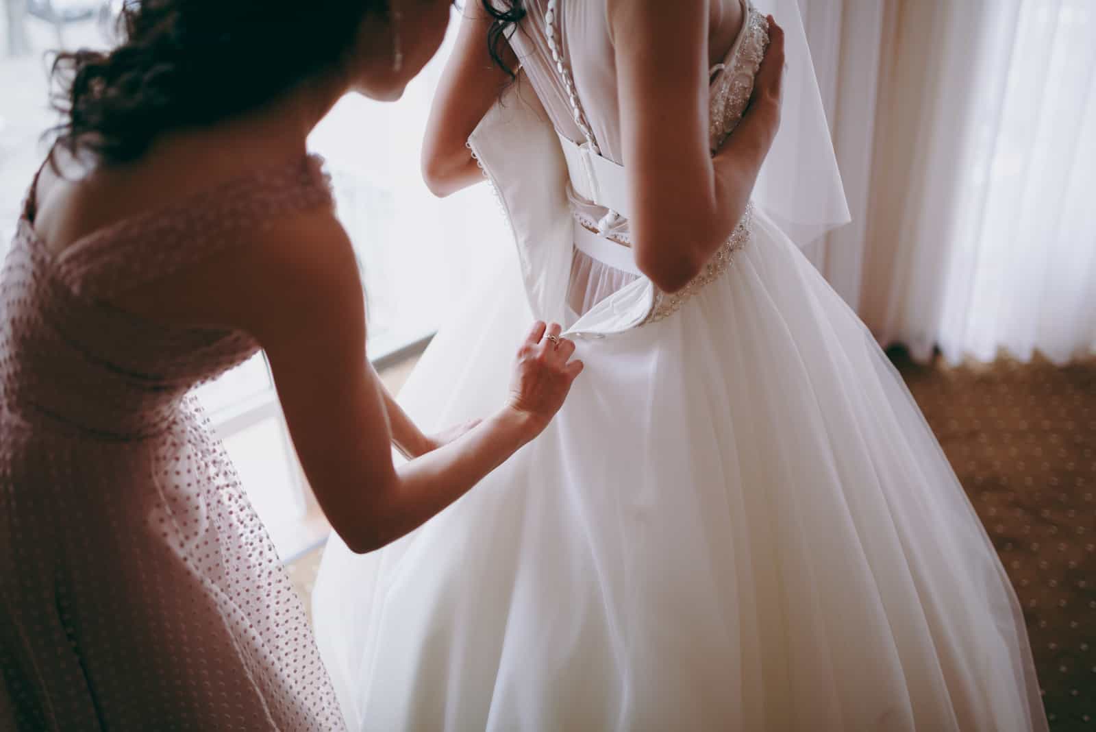 Trauzeugin hilft der Braut beim Kleid